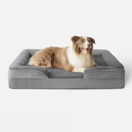 hond ligt ontspannen op grote grijze hondenmand met zachte textuur.