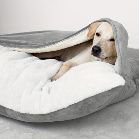 Hond ligt ontspannen in grijs pluche bed met witte fluffy binnenkant en overhangende flap.